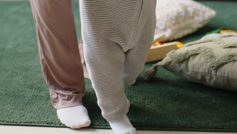baby making first steps with help of mom