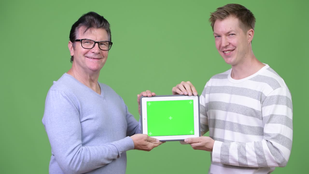 Senior handsome man and young handsome man showing digital tablet together