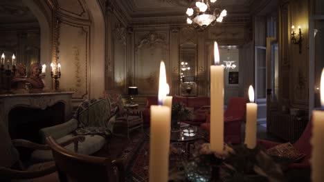 slow pan of a moody room passing by burning candles within a large mansion