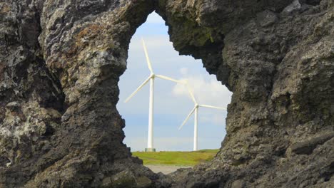 Rotierende-Windmühlen,-Eingerahmt-Durch-Felslochformationen-An-Der-Küste