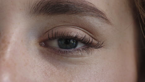 mujer de cerca hermosa apertura de ojos azules mirando a la cámara pupila enfoque usando maquillaje