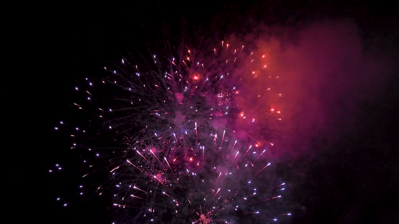 Fireworks of various colors exploding in the dark sky during a celebration