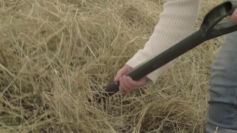 farmer turning hay stack with fork