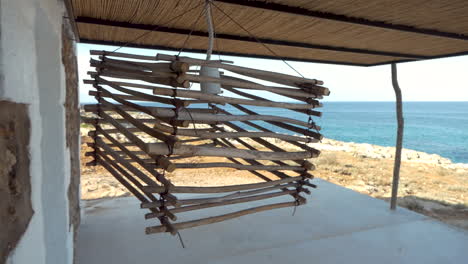 handmade lamp made with pieces of wood and metal wire swaying in the wind in front of the ocean