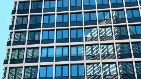 facade of the high-rise building with large windows. office building reflecting the house next to it. low angle view