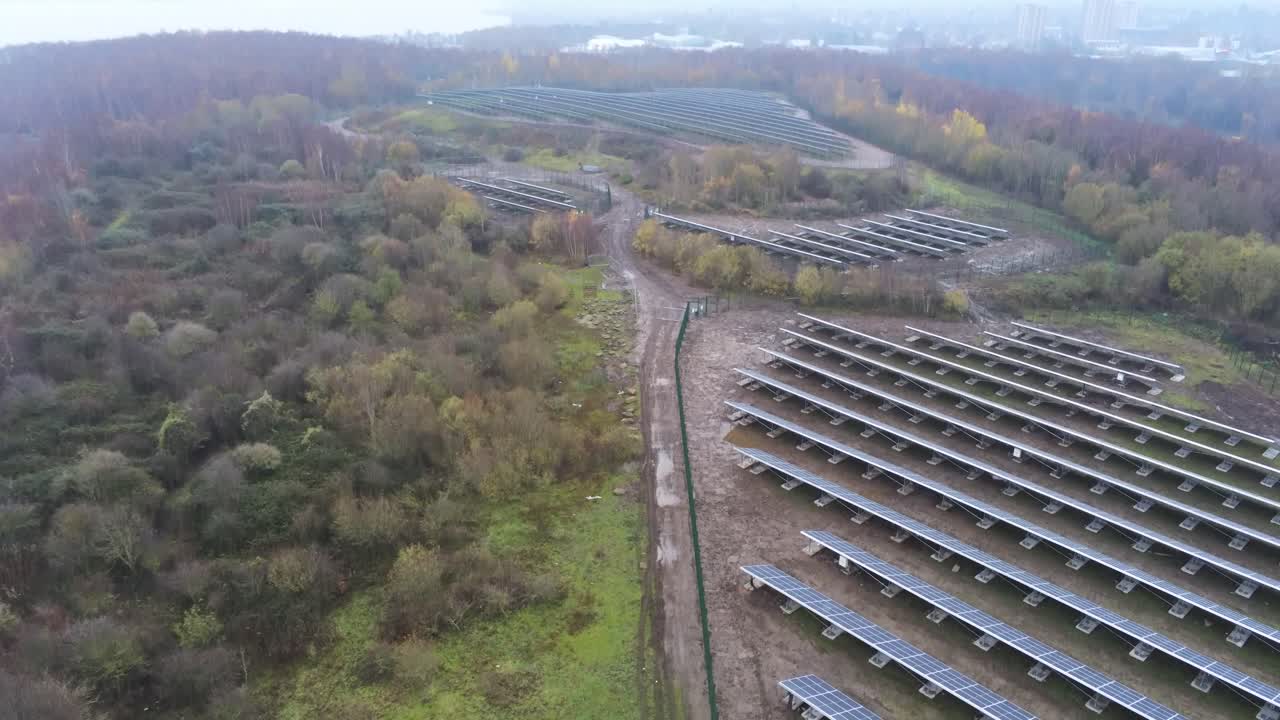 Solar panel array rows aerial view misty autumn woodland countryside rising tilt up