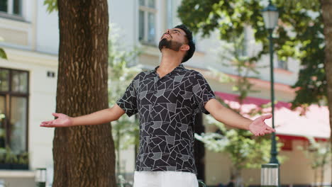 indian man taking a deep breath of fresh air relaxing taking a break resting meditating calm down