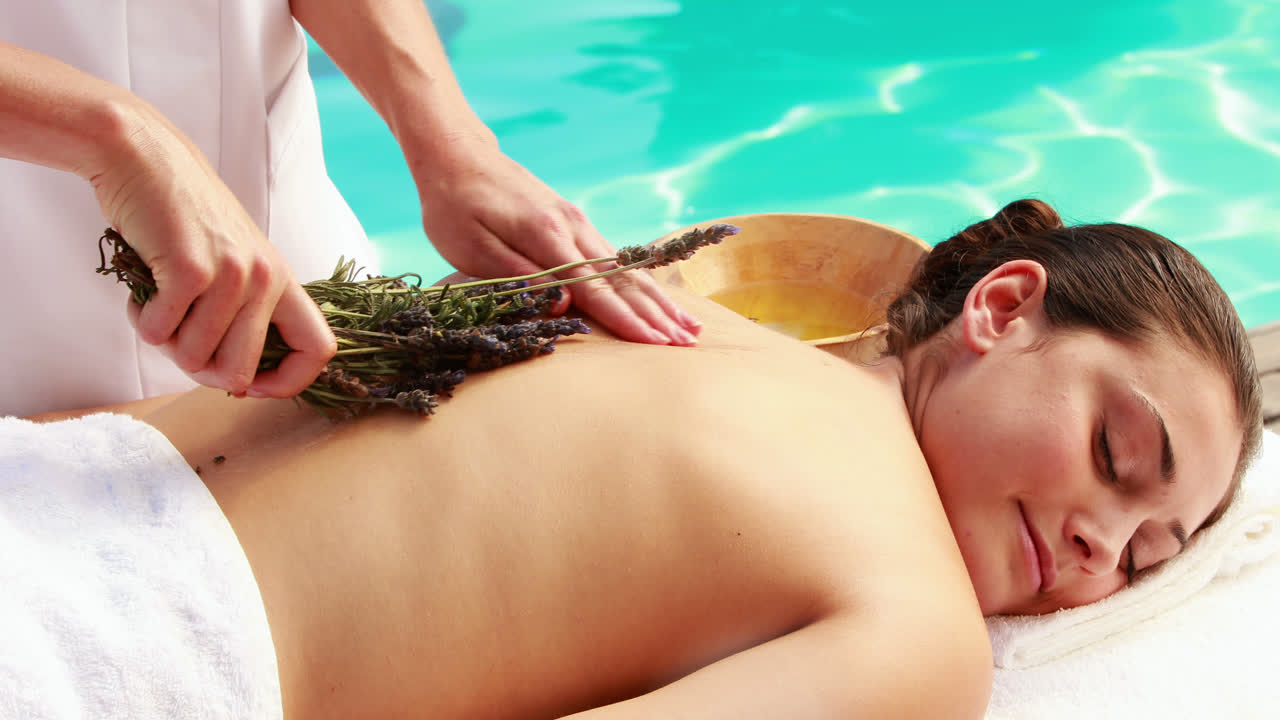 미용 치료사 가 여성 의 등 을 라벤더 로 문지르고 있다