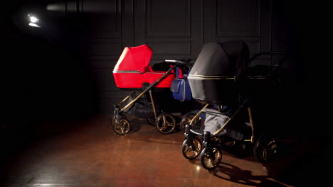 dark room with fashionable baby strollers of different colors. three perambulators for newborn babies are pushed to the foreground.