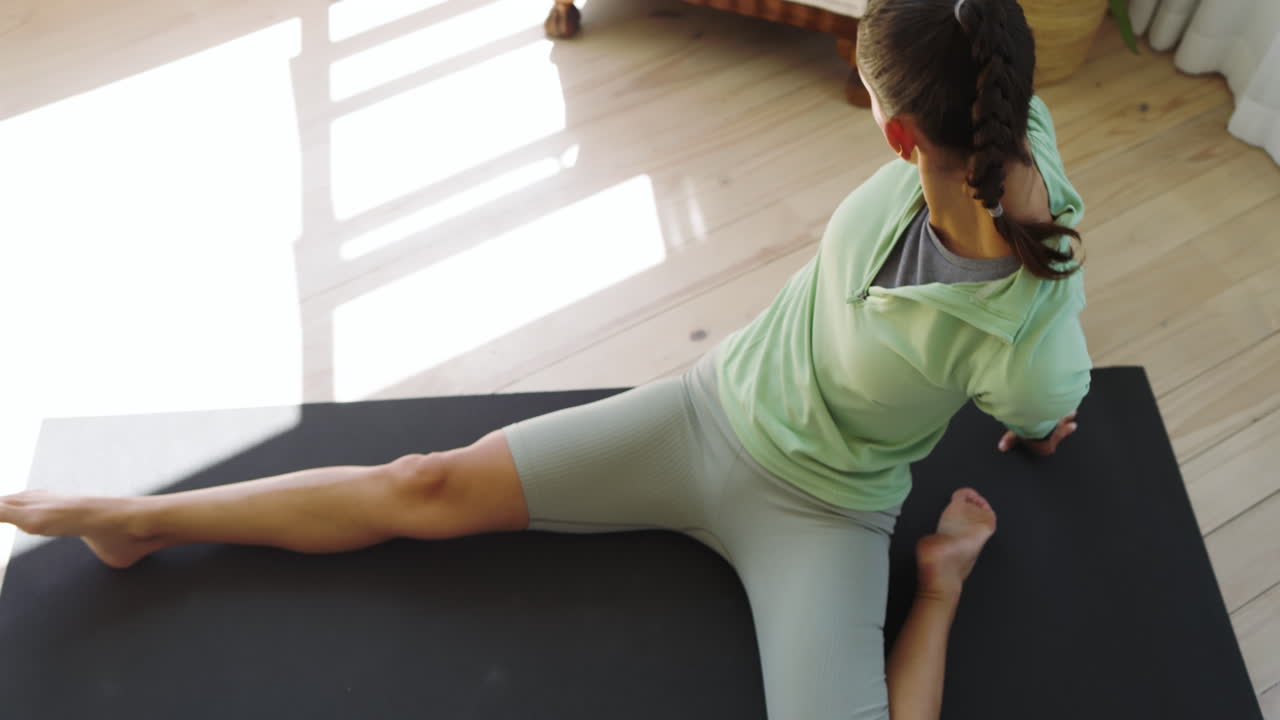 Woman stretching on yoga mat at home, focusing on flexibility and relaxation