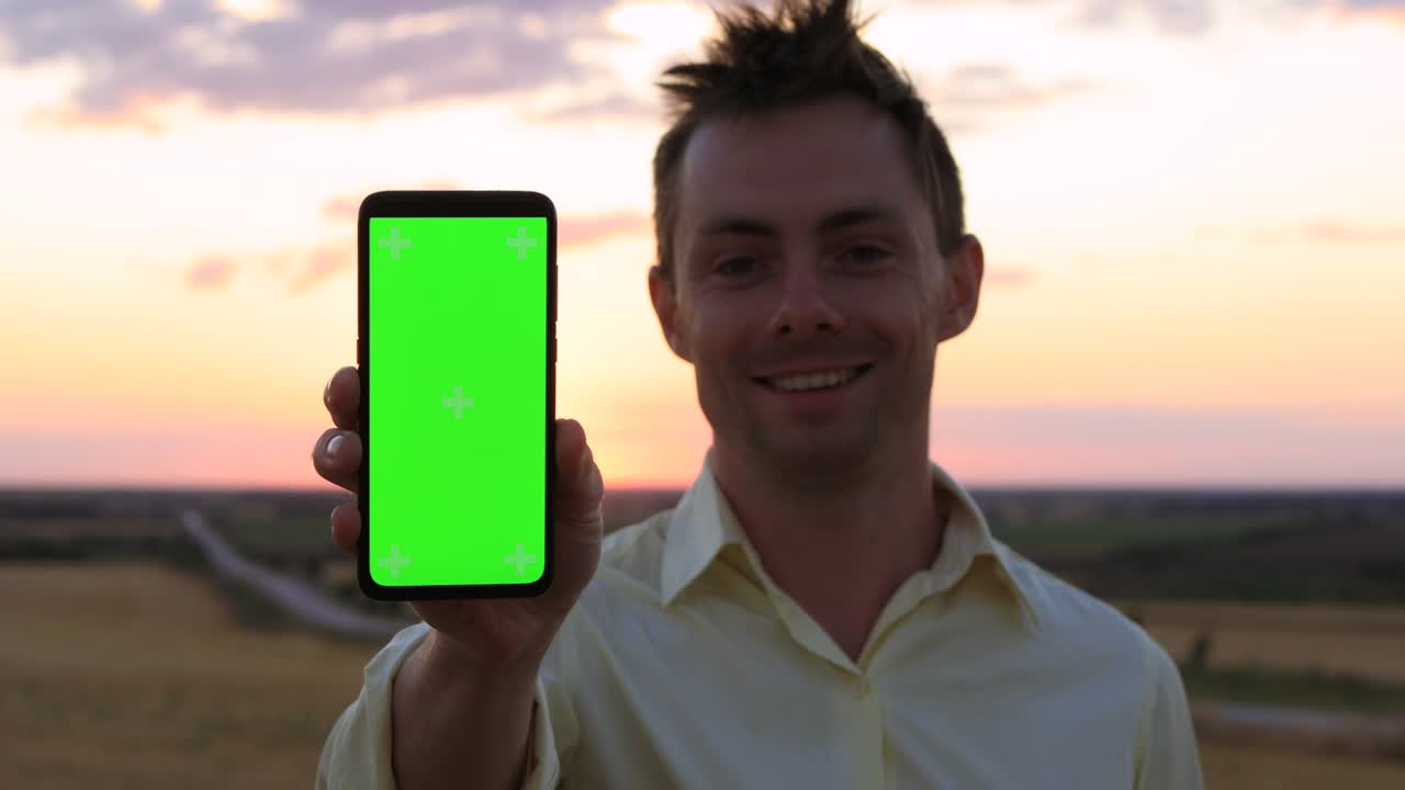 hombre muestra teléfono inteligente con pantalla verde vacía