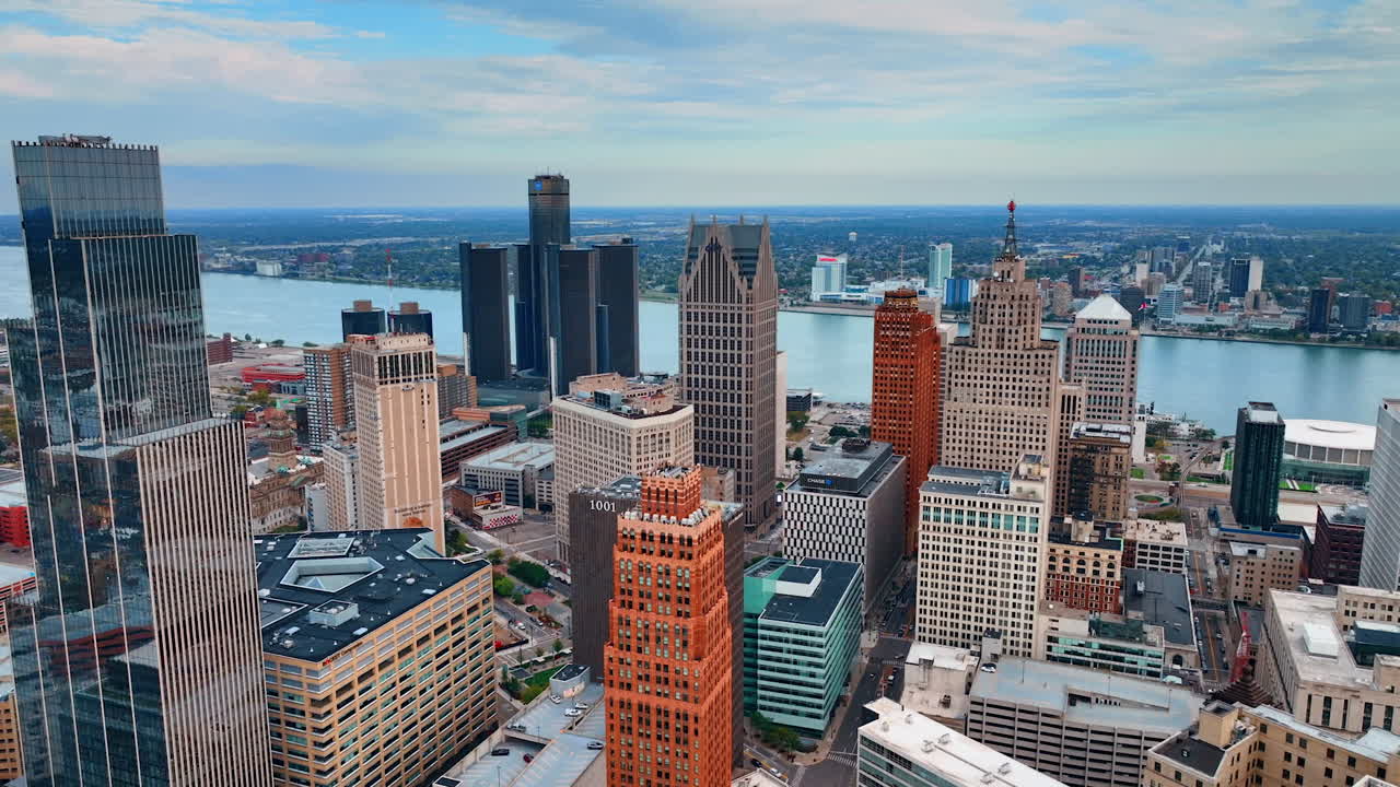 Beautiful diverse high-rise buildings in the downtown of modern American city. Waterscape of the river crossing the city at backdrop. Drone footage over Detroit, Michigan on overcast day