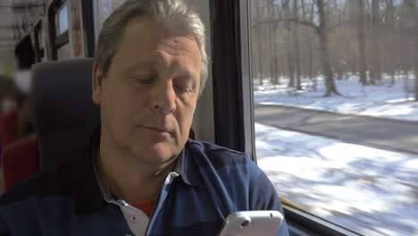 mature man using smartphone while train trip