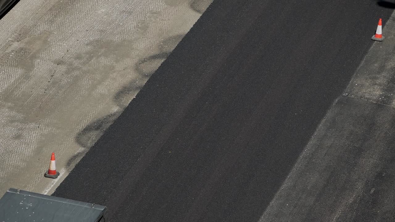 위에서 본 도시 거리를 포장하는 동안 공압식 도로 롤러 차량으로 아스팔트 압축