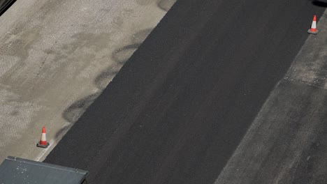 Asphalt-compaction-with-pneumatic-road-roller-vehicle-during-pavement-of-city-streets-seen-from-above