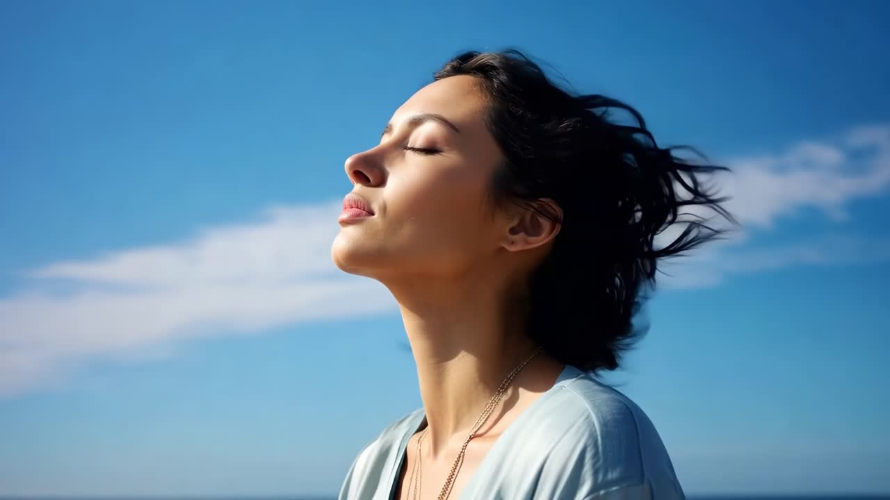 Close-up video of a serene woman with closed eyes against a blue sky