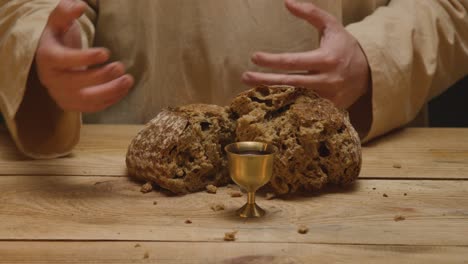 Close-Up-Shot-Of-Man-Wearing-Robes-Representing-Figure-Of-Jesus-Christ-Blessing-Broken-Bread-And-Wine-