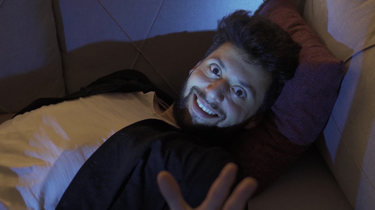 joven esquizofrénico mirando sus manos riendo y loco.