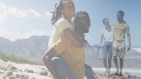 compuesto de una feliz pareja afroamericana a caballo, y abrazando caminando por la playa
