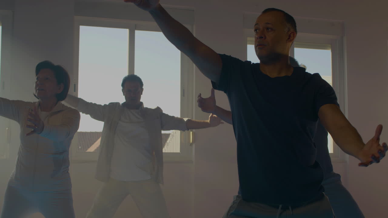 grupo de personas mayores practicando tai chi en el gimnasio con sofá
