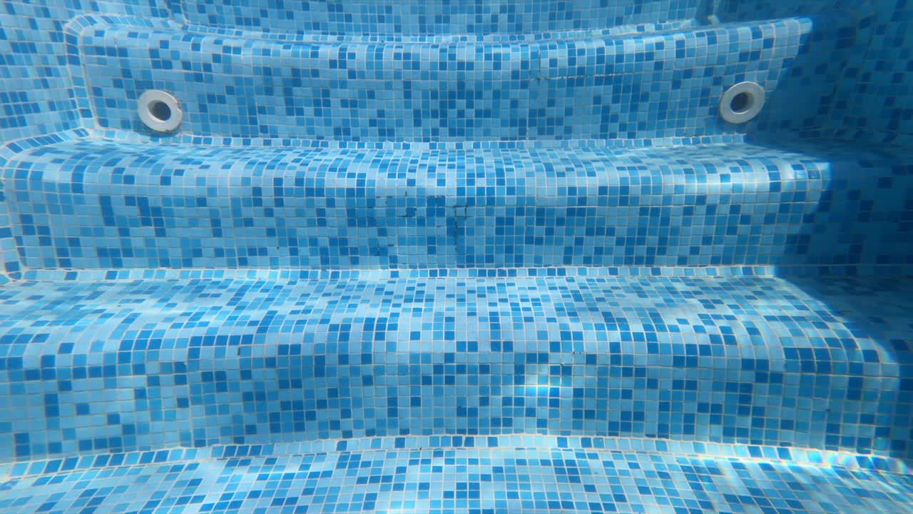 Man filming himself diving in the pool wearing swimming goggles