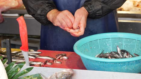 fishmonger cleaning fresh fish at a market stall