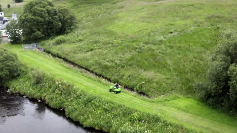 Schneiden-Von-Gras-Entlang-Eines-Schottischen-Flussufers-Auf-Einer-Fahrt-Mit-Dem-Rasenmäher-Im-Sommer