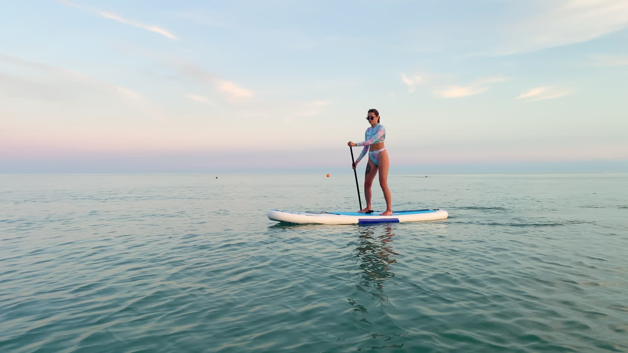 mujer stand-up paddleboarding al atardecer