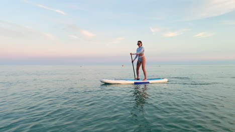 woman stand-up paddleboarding at sunset