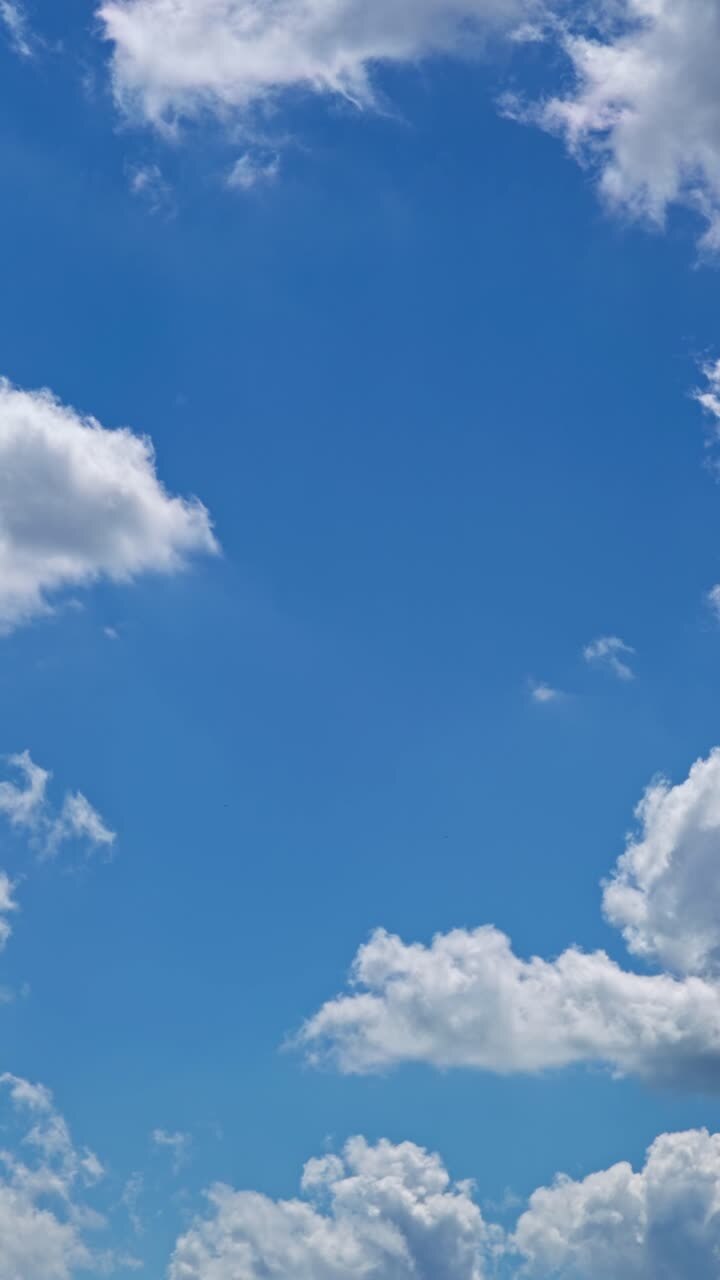 Clouds float in a blue sky during the bright afternoon