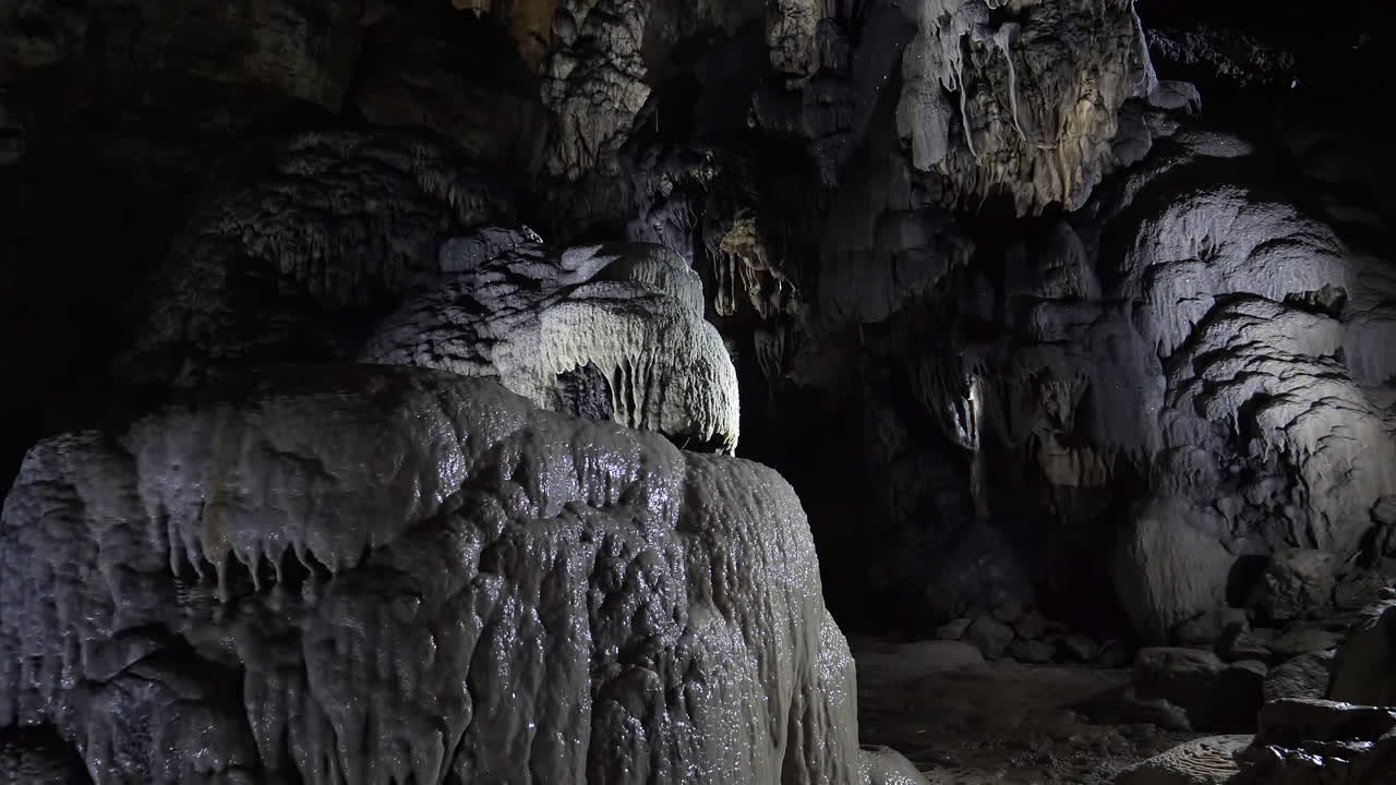 ver el interior de una cueva oscura con formaciones rocosas de estalagmitas