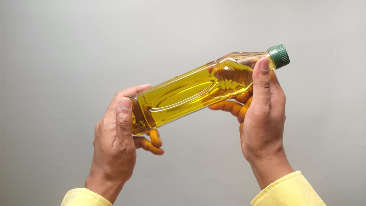 persona que sostiene una botella de aceite