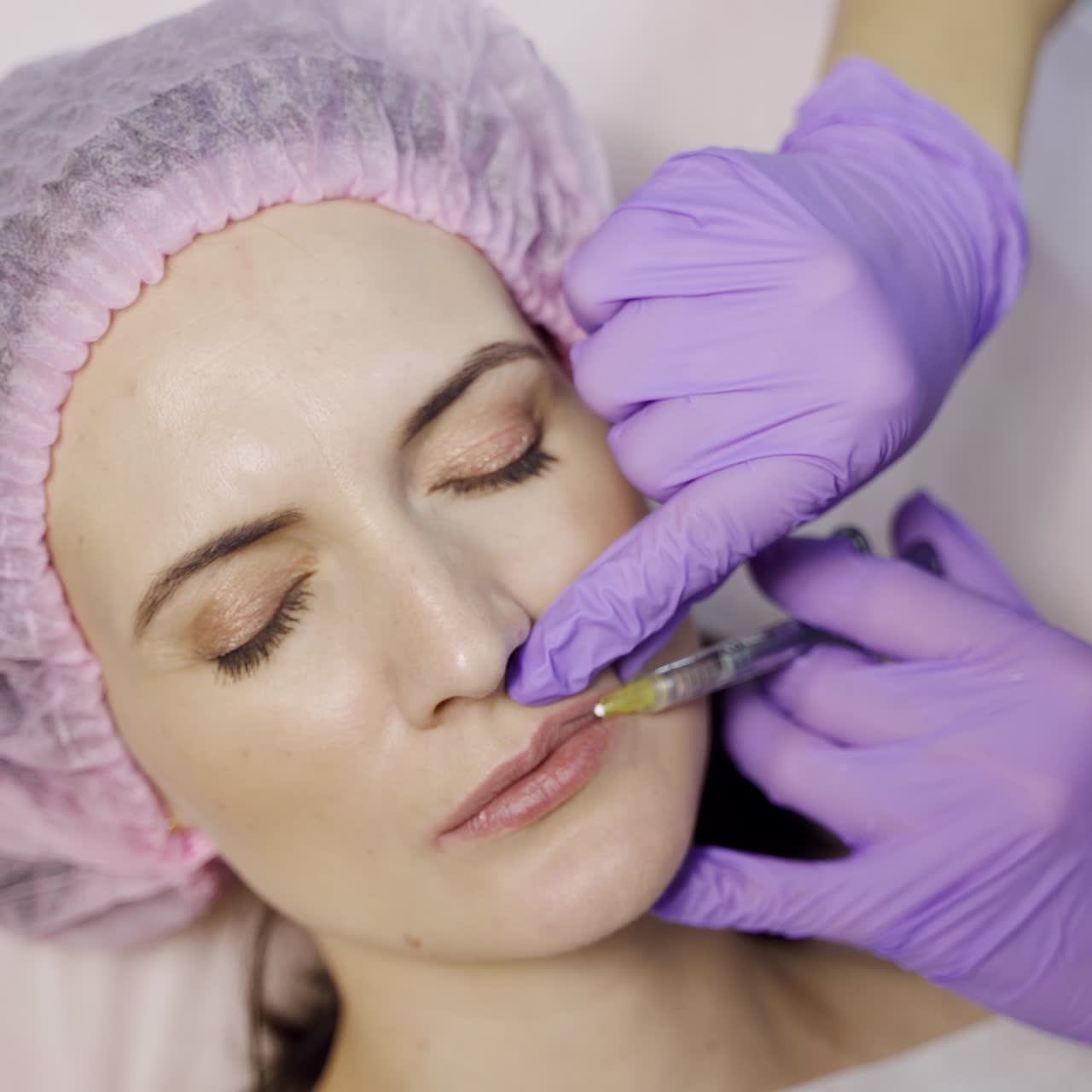 Beautiful woman is doing a lip augmentation procedure in a beauty salon. Botox in the lips area. Modern cosmetology. Close-up