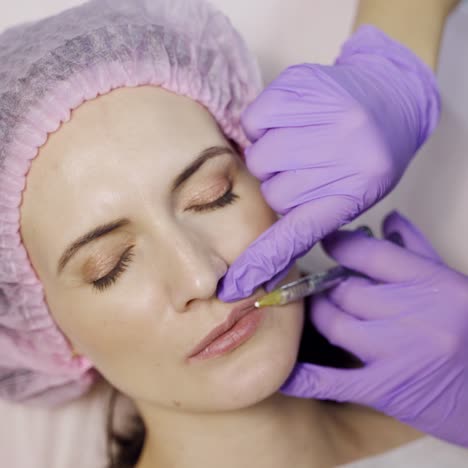 beautiful woman is doing a lip augmentation procedure in a beauty salon. botox in the lips area. modern cosmetology. close-up