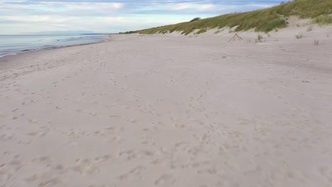 aerial: low and slow flying above sandy beach near the seaside