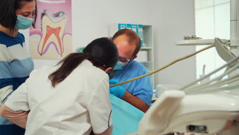 Stomatologist-with-mask-and-gloves-using-drill-tool-for-cleaning-teeth-of-kid