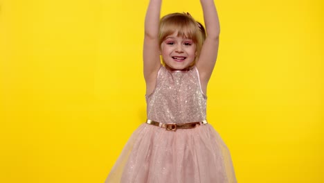 hello or bye. little smiling blonde child kid girl waving greeting with hand on yellow background