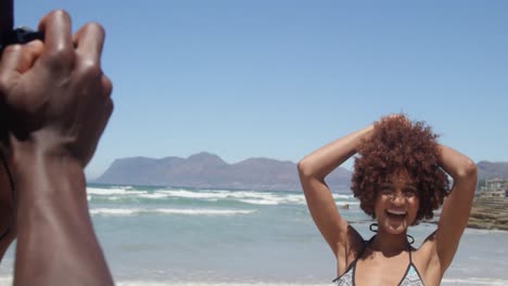 young african american man taking pictures of woman with digital camera on the beach 4k