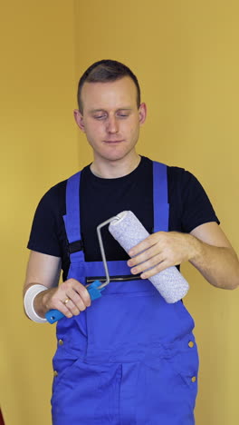 portrait of a handsome man worker with tool for paint. painter holding new paint roller before starting interior decoration. offering professional painting services. vertical video