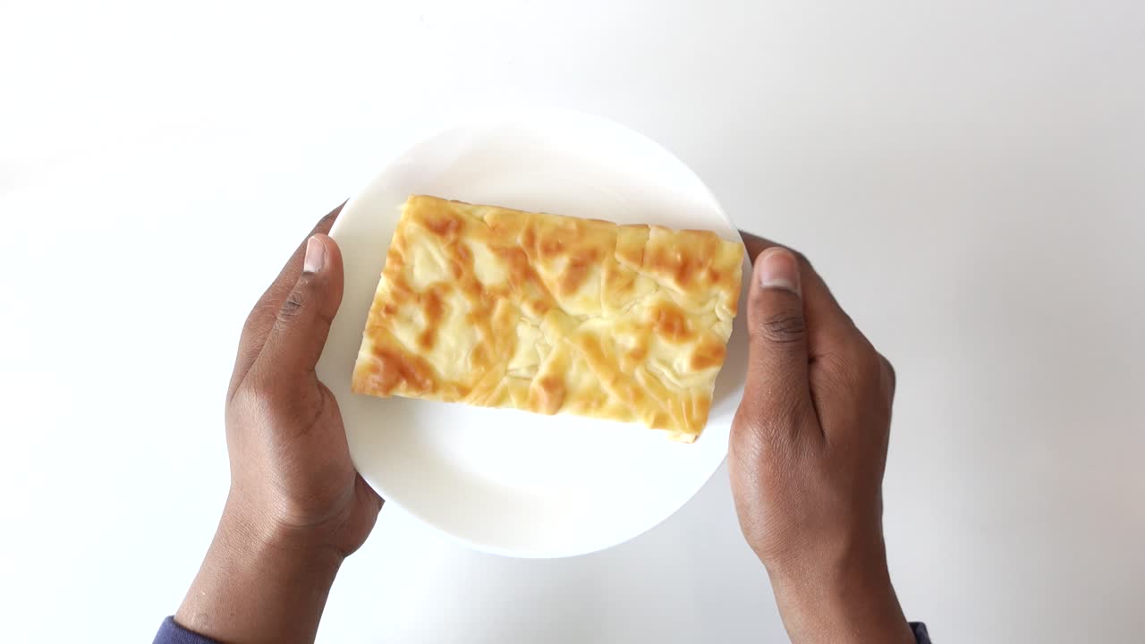 persona sosteniendo una pieza de pastel horneado en un plato