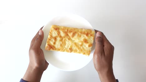 person holding a piece of baked pastry on a plate