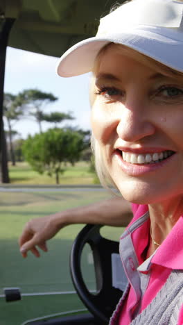 happy female golfer sitting in golf buggy