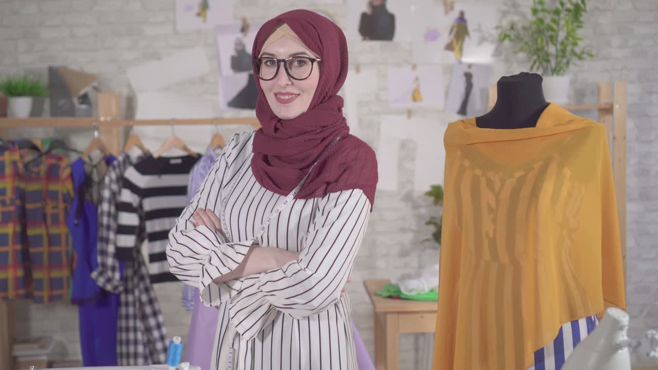 Portrait of a young muslim woman fashion designer in National headscarf with a measuring tape next to the mannequin in his Studio