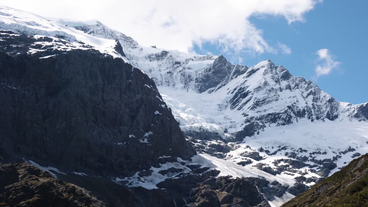 Wide view of snow covered mountains and glacier on a sunny day at Rob Roy Glacier, Wanaka, New Zealand.