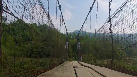 hombre caminando en un puente colgante de hierro antiguo desde un ángulo bajo se toma un video en nongjrong meghalaya india