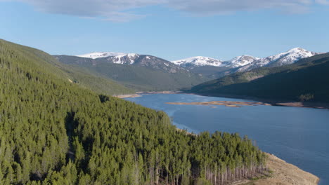 aerial drone scenic landscape of lake reservoir in pine tree forest in colorado snow-capped rocky mountains