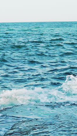 crests of the waves are breaking on the reefs near the shore in the summer. seascape. slow motion. aerial view vertical video