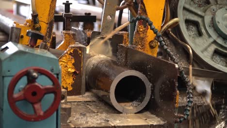 industrial band saw, cutting metal pipe, coolant in yellow scene, industrial tools