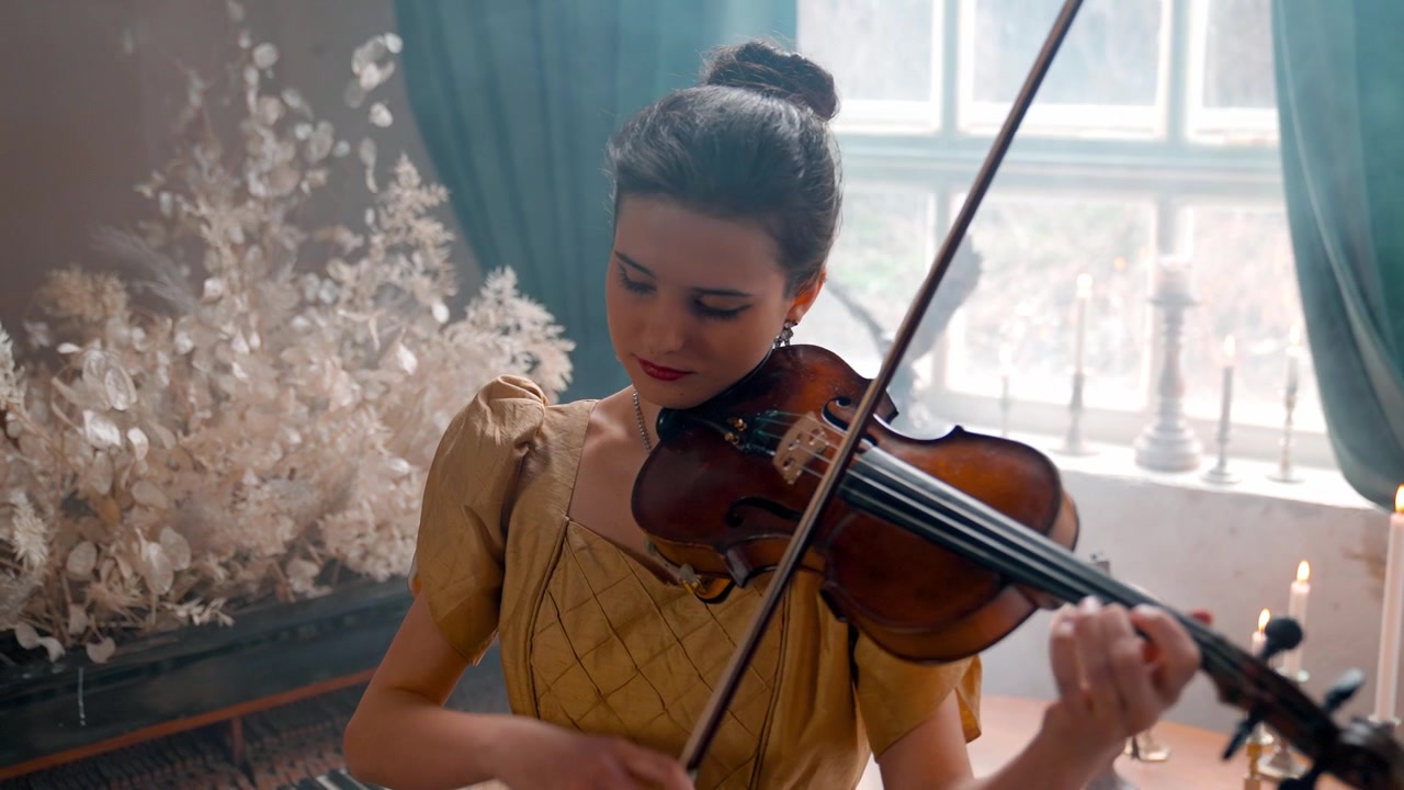 Donna elegante in abito vintage che suona il violino in una stanza velata