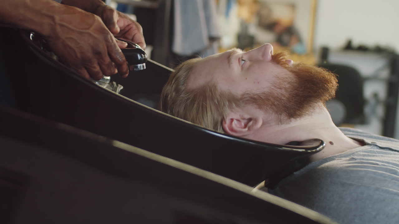 hombre lavando el cabello en la barbería